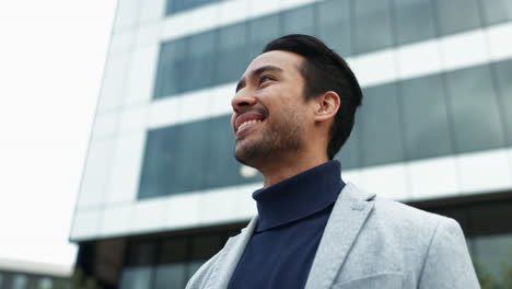 a man in a suit jacket smiles confidently in front of a city building