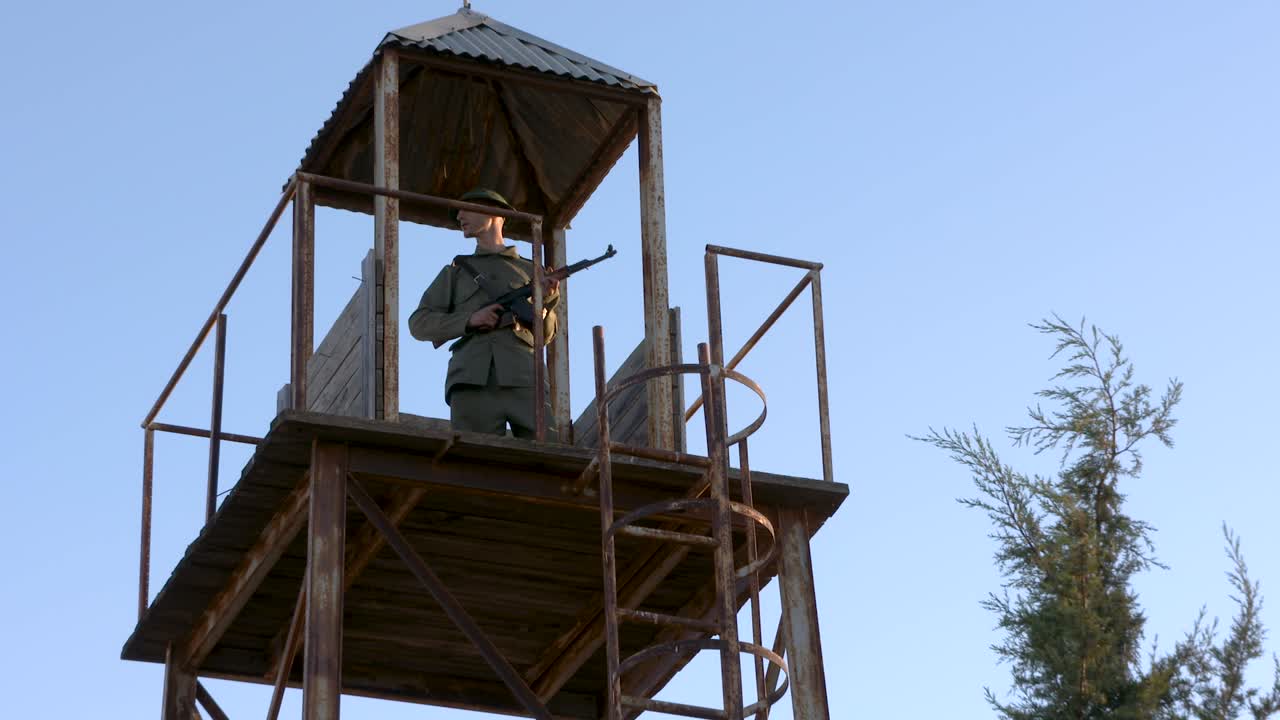 un guardia del ejército armado está de guardia, en lo alto de una torre de vigilancia