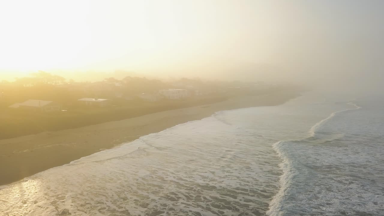 Stunning aerial view of a empty beach at a foggy morning - Forest Fire - 4k - Glowing Sky - Westcoast Oregon, Rockaway Beach