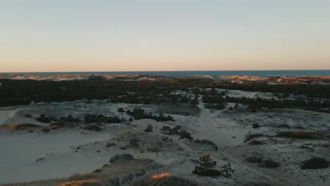 Aerial-descending-shot-of-people-exploring-the-Provincetown-Dunes-at-sunset