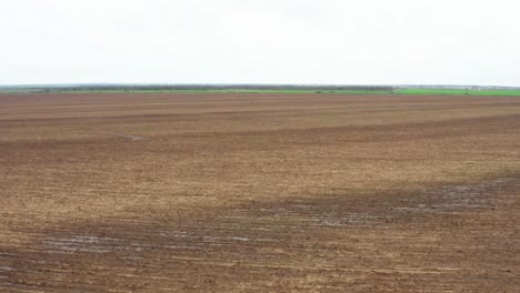 Low-altitude-fly-over-brown-arable-dirt-soil-prepared-for-farming