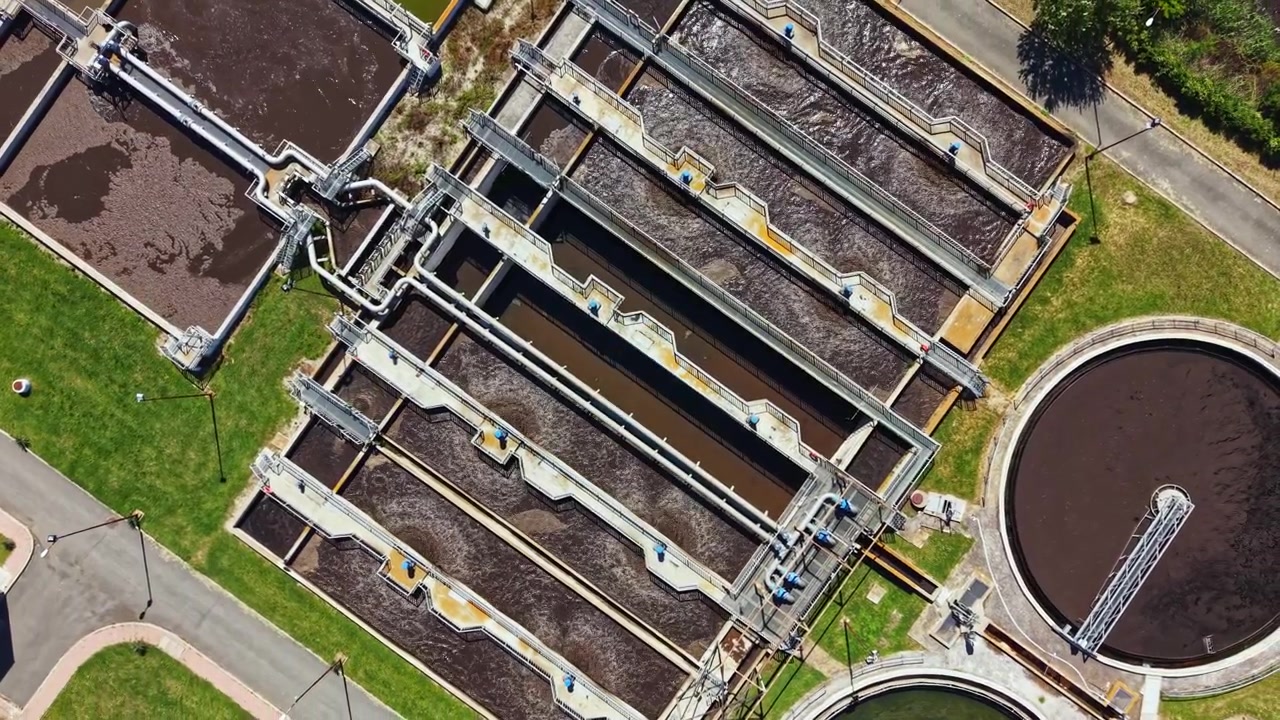 Water treatment facility located in a city showing multiple tanks and channels under clear sky during daytime