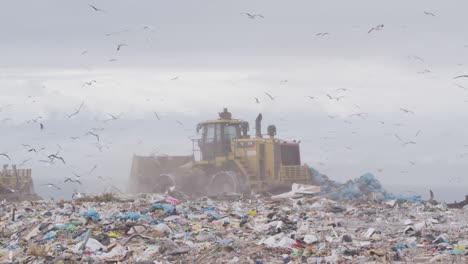 vehicles clearing rubbish piled on a landfill full of trash