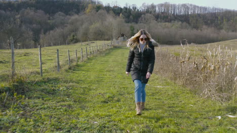 young white woman model smiling and walking on agricultural field in autumn season