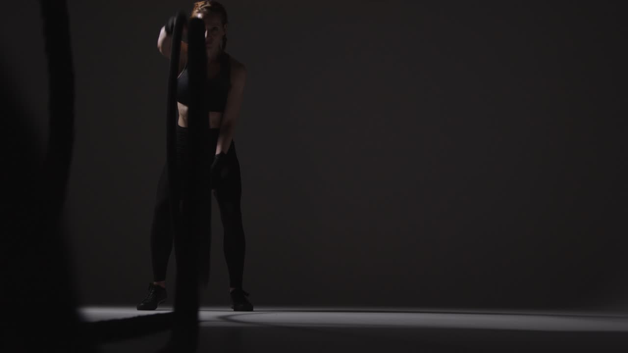 성숙한 여성이 체조 옷을 입고 전투 로프로 심장 운동을 하는 스튜디오  1