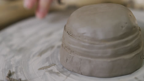 close up view of female potter using loop tool for finishing pottery at pottery studio