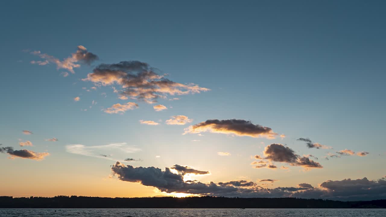 Beautiful hyper time lapse golden hour to blue to black clouds boiling sunset looking out over Puget Sound, pan down zoom in