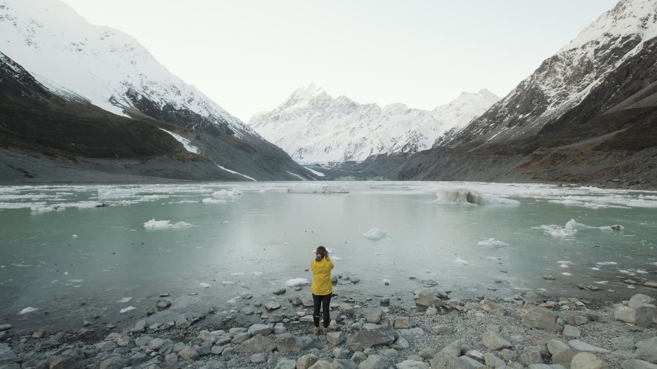 Optagelse der viser en pige, der fotograferer Hooker Lake i New Zealand på en kold vintereftermiddag