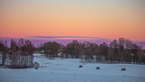 Zeitraffer-Eines-Gelben-Himmels,-Der-Sich-über-Einer-Verschneiten-Landschaft-Mit-Einer-Hütte-Rosa-Färbt