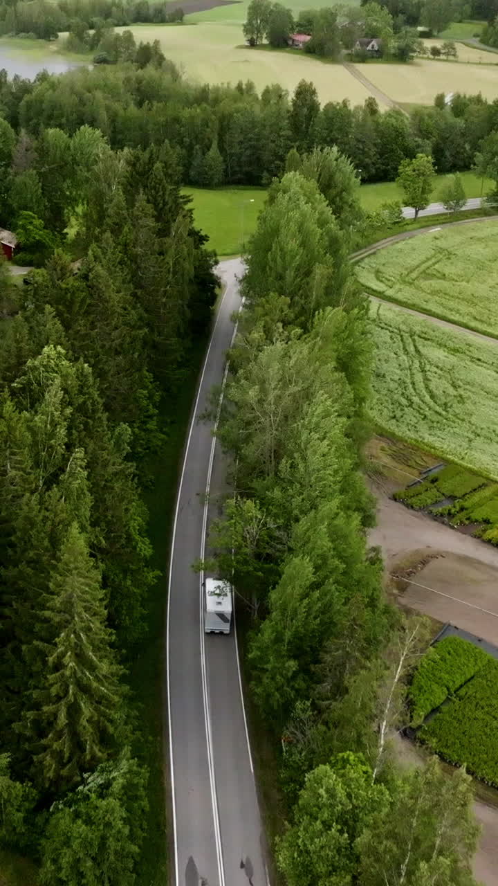 Vertical drone shot following a RV driving past a plant nursery in rural Finland