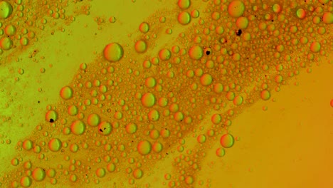 el líquido graso verde+naranja fluye sobre una superficie con burbujas y suciedad