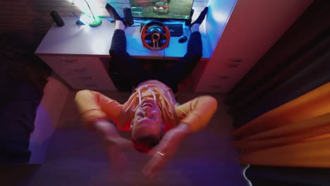 top view of man driving simulator. young man with pc computer playing car racing video game at home