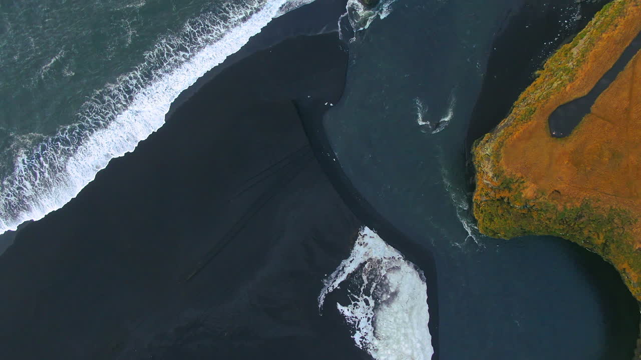 Drone view of waves in the sea crashing ashore from an aerial vantage point near the mountains in Iceland