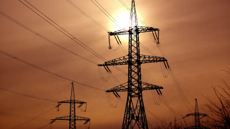 transmission lines against the evening sky. high-voltage electric towers with wires on the setting sun background. black pylons with electricity.