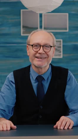 vertical video: pov of elderly aged man waving during a video conference