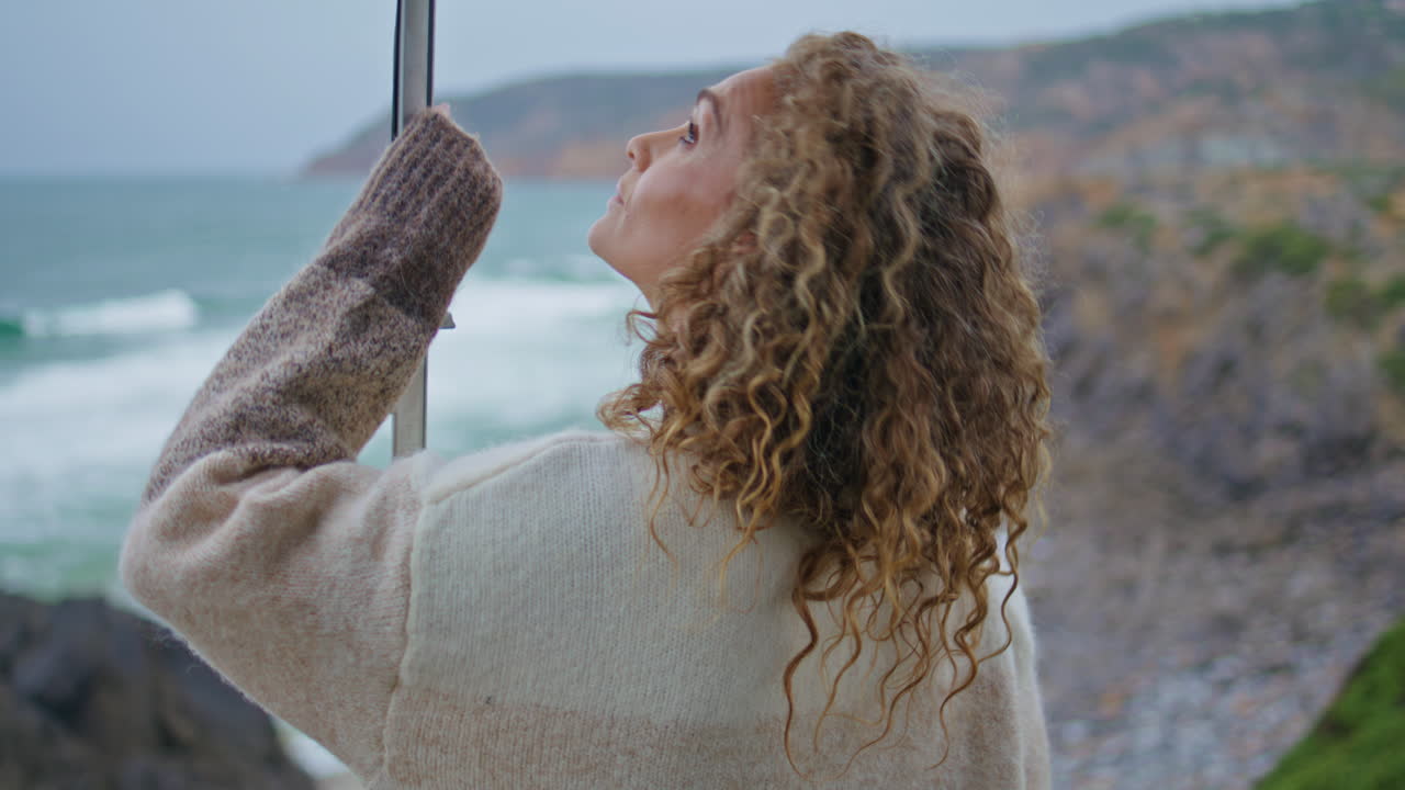 mujer melancólica buscando belleza del océano de pie costa sombría primer plano vista trasera.