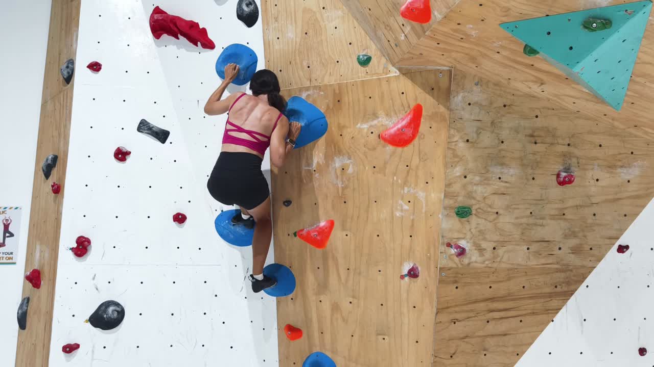 mujer bouldering en la pared de escalada interior