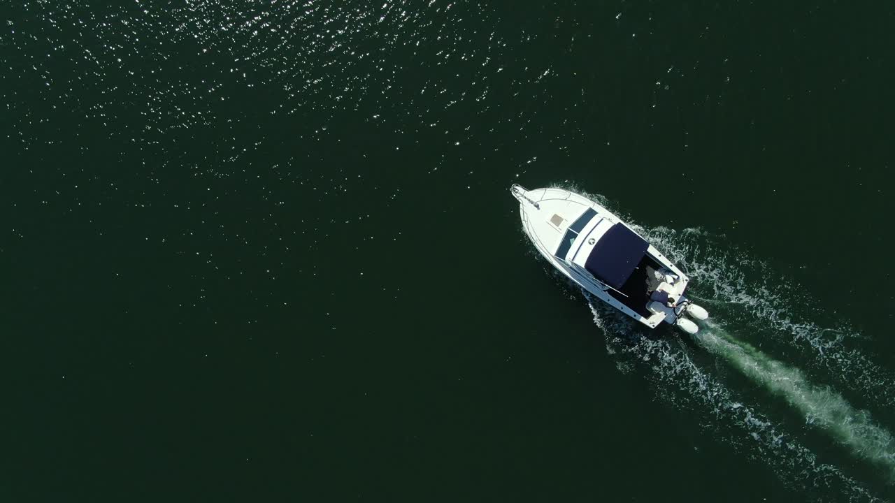 Spiraling overhead shot of fishing boat leaving harbour