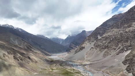 aerial drone shot flying over ladakh’s majestic mountains under clear, crisp skies.