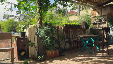 Tranquilidad-Matutina:-Acogedor-Jardín-Exterior-Con-Sillas-De-Madera,-Mesa,-árboles-Y-Plantas-En-Macetas