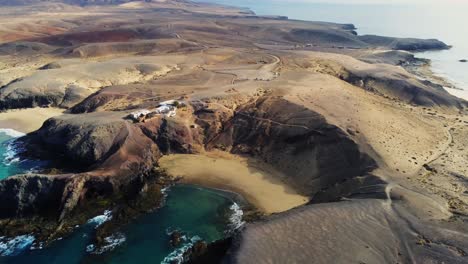 white remote buildings on coastal cliff of lanzarote island, aerial drone view