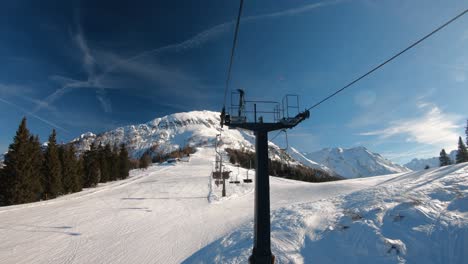 going-up-a-hill-on-a-chair-lift-with-a-snowy-mountain-on-the-horizon-and-dark-sky-above
