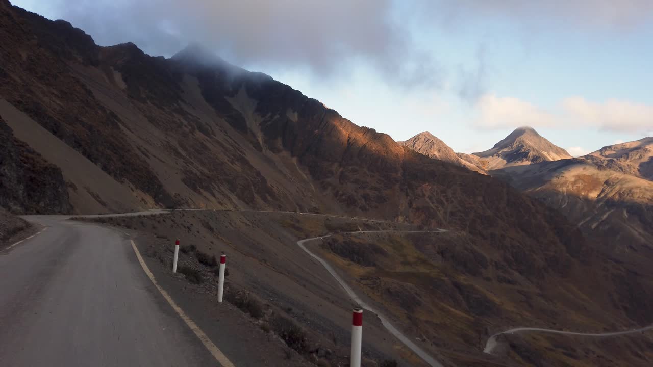 Driver’s point of view on a winding high-altitude road through steep, barren mountain slopes near Abra Amparaes in the Sacred Valley of the Peruvian Andes, Cusco, Peru
