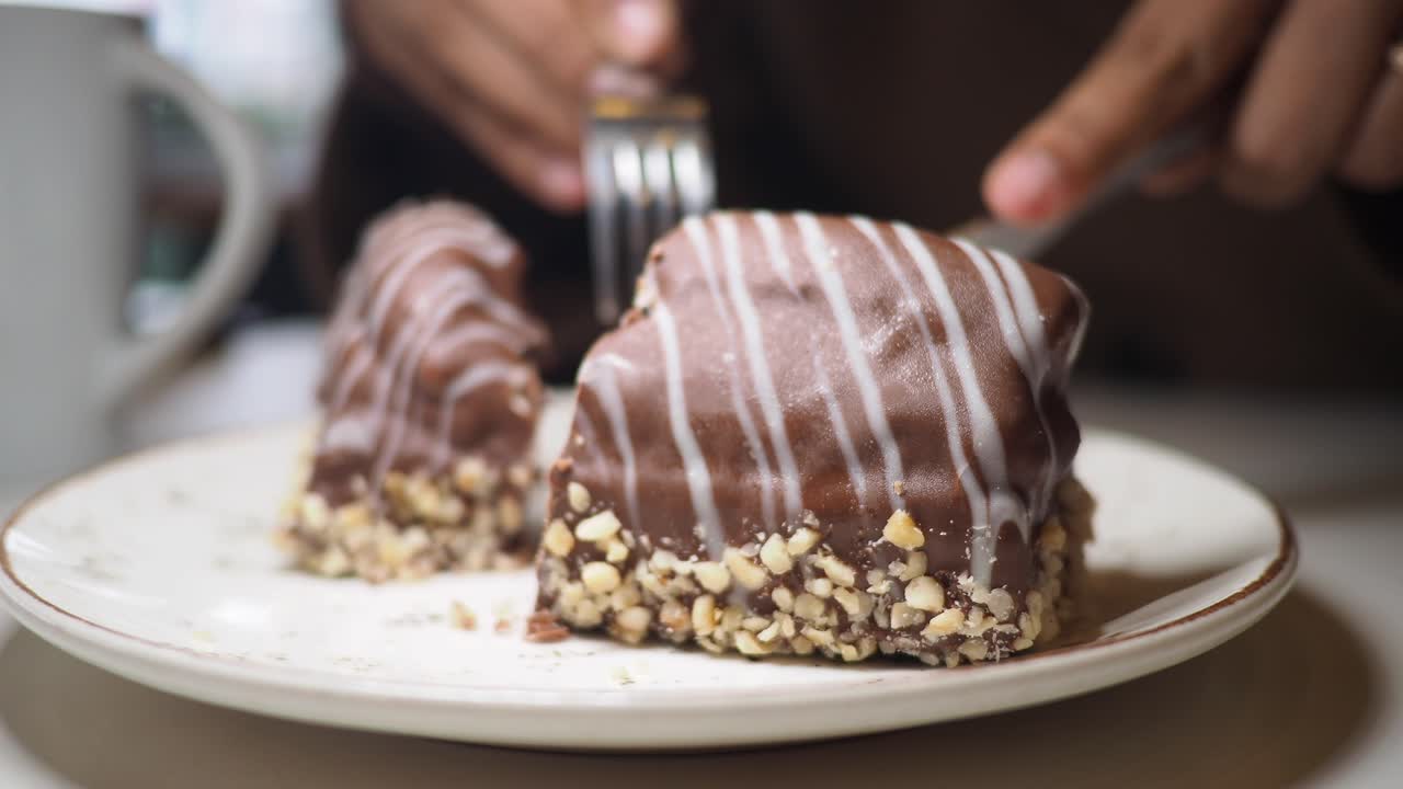 Primo piano di mani che tagliano una torta al cioccolato con noci