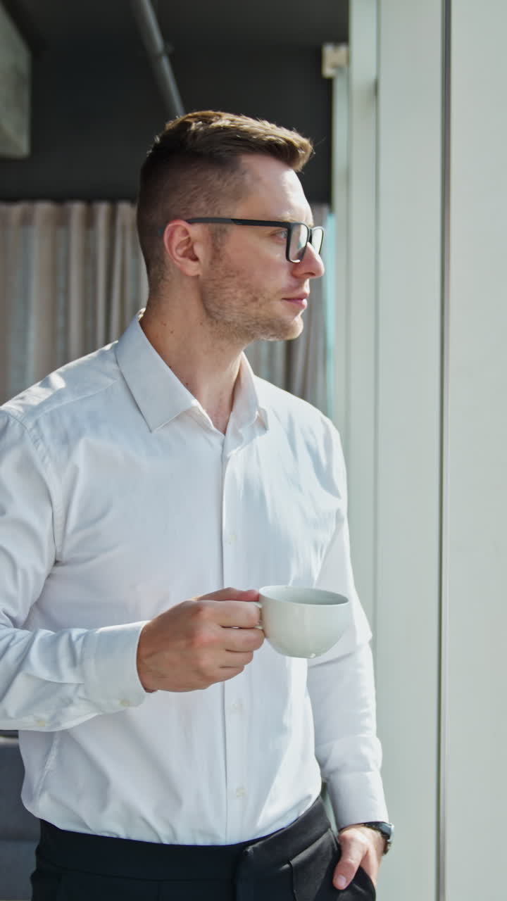 Uomo d'affari che guarda fuori dalla finestra con il caffè
