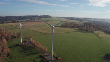 Windkraftanlagen-An-Einem-Sonnigen-Tag-In-Der-Nähe-Des-Dorfes,-Umgeben-Von-Einer-Wiese