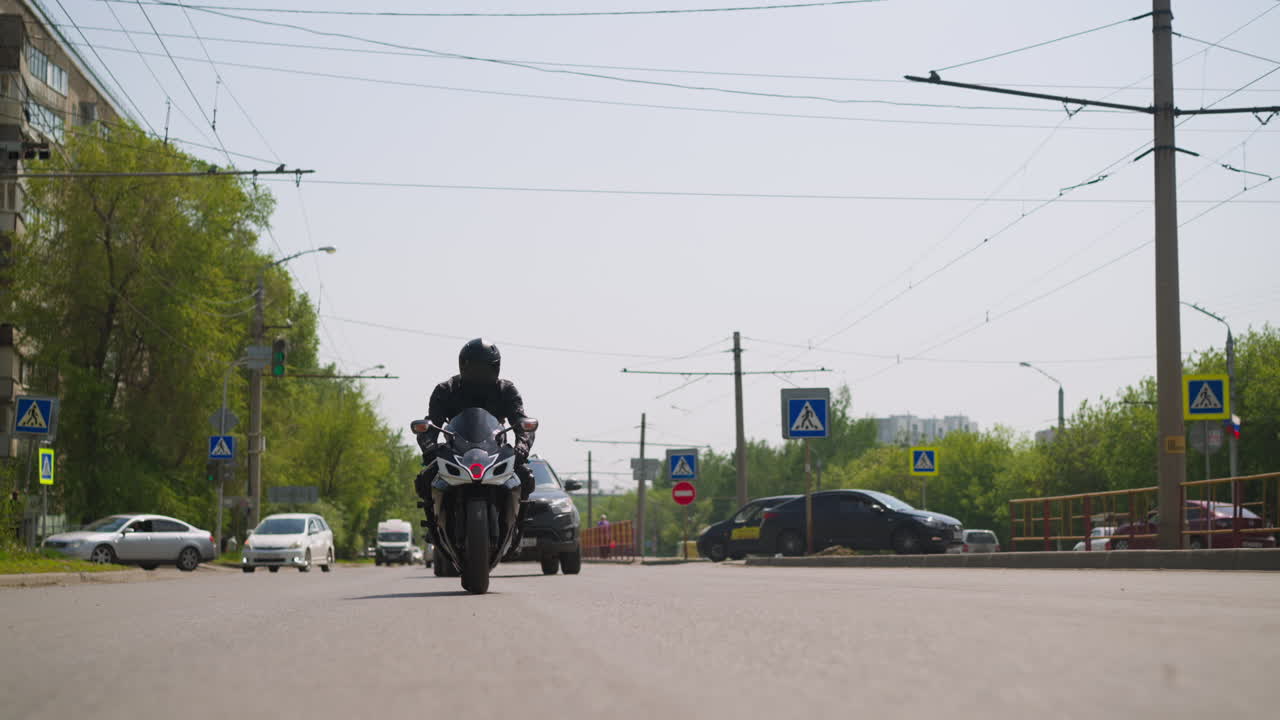 человек ездит на мотоцикле по большой дороге с машинами в городе