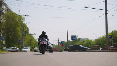 hombre monta motocicleta a lo largo de una gran carretera con coches en la ciudad