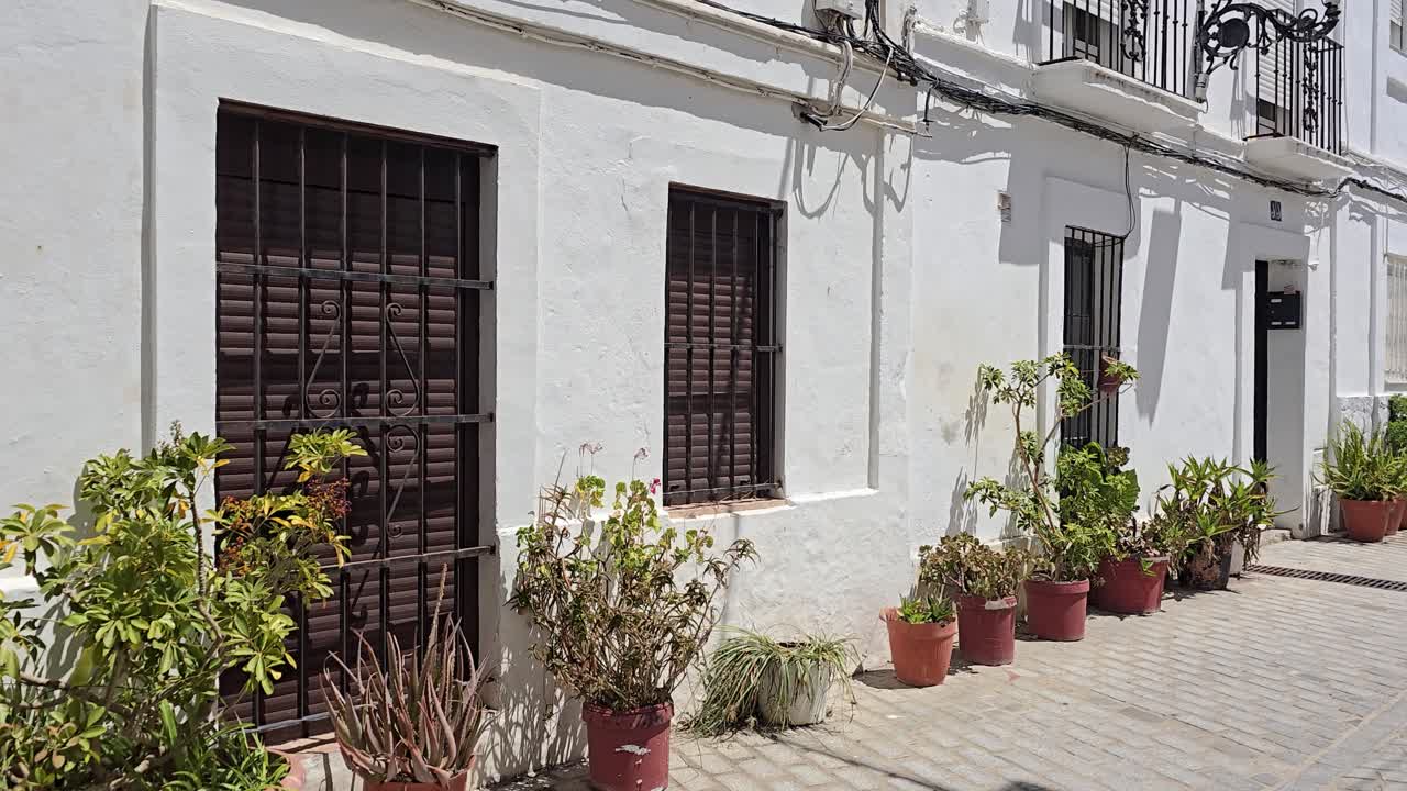 Narrow street with white houses and potted plants in Tarifa, Spain