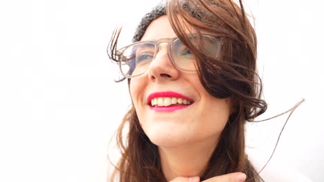 cute woman with glasses and messy hair smiling at camera on windy day