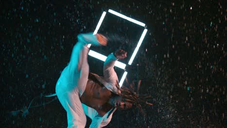 black capoeira dancer performing kick in rain in super slow motion