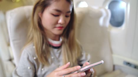 Asian-woman-using-mobile-phone-in-airplane