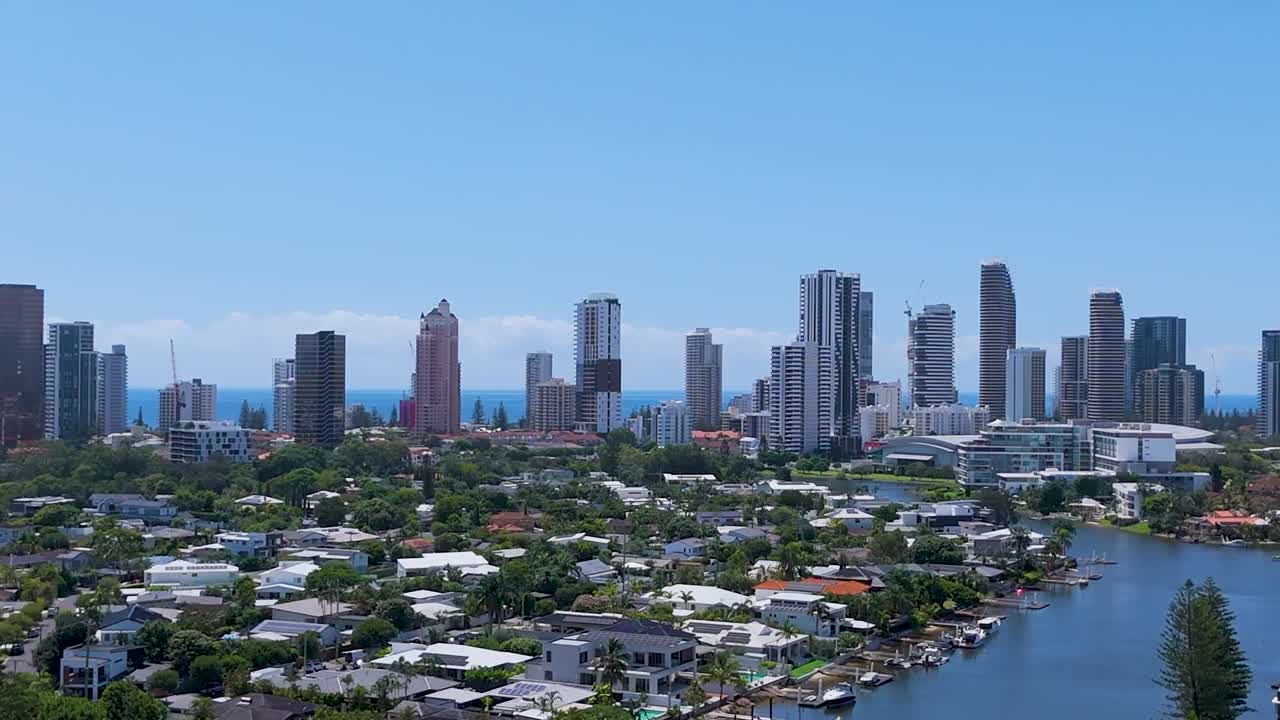 Aerial footage highlighting skyscrapers and residential areas along a scenic waterway under a clear blue sky.