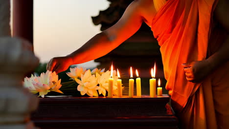 monk arranging lotus flowers and lighting candles at a temple