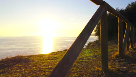 drone panning left and passing between the wooden fence to reveal the coastline sunset