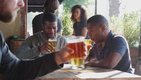 two male friends meeting outdoors in sports bar enjoying drink before game