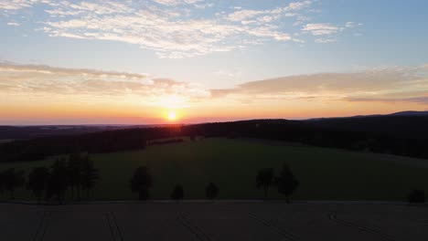 Ein-Wunderschöner-Goldener-Blick-Auf-Den-Sonnenuntergang-Von-Einer-Drohne-In-Den-Bergen,-Während-Die-Kamera-Langsam-Auf-Den-Boden-Sinkt