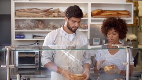 manager training a woman behind the counter at sandwich bar