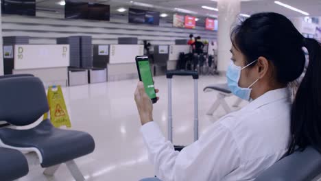 4k asian tourist women wear protective face masks for outbreak coronavirus sit on social distancing chair use smartphone for contact with friend or family. women use mobile phone with green screens.