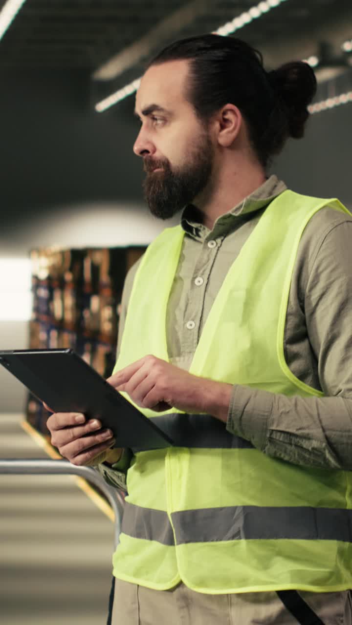 Video verticale. Dipendente del magazzino che controlla la logistica degli ordini su tablet in un centro di distribuzione.