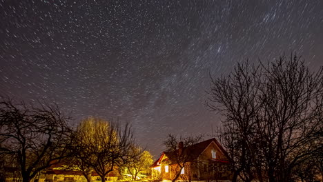 long exposure of stars moving at the night sky over the trees and house