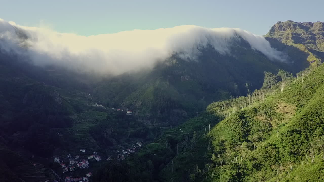 vista aérea moviéndose hacia las nubes cayendo rápidamente sobre la línea de la cresta en las montañas