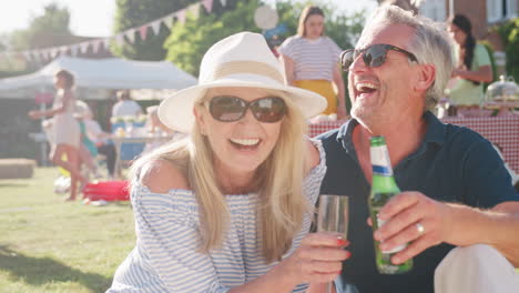 slow motion portrait of mature couple at summer garden fete celebrating with drinks