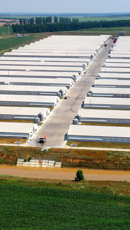 agriculture business among environment. modern farm buildings on field. large territory of farmland for livestock on green meadow. view from above. vertical video