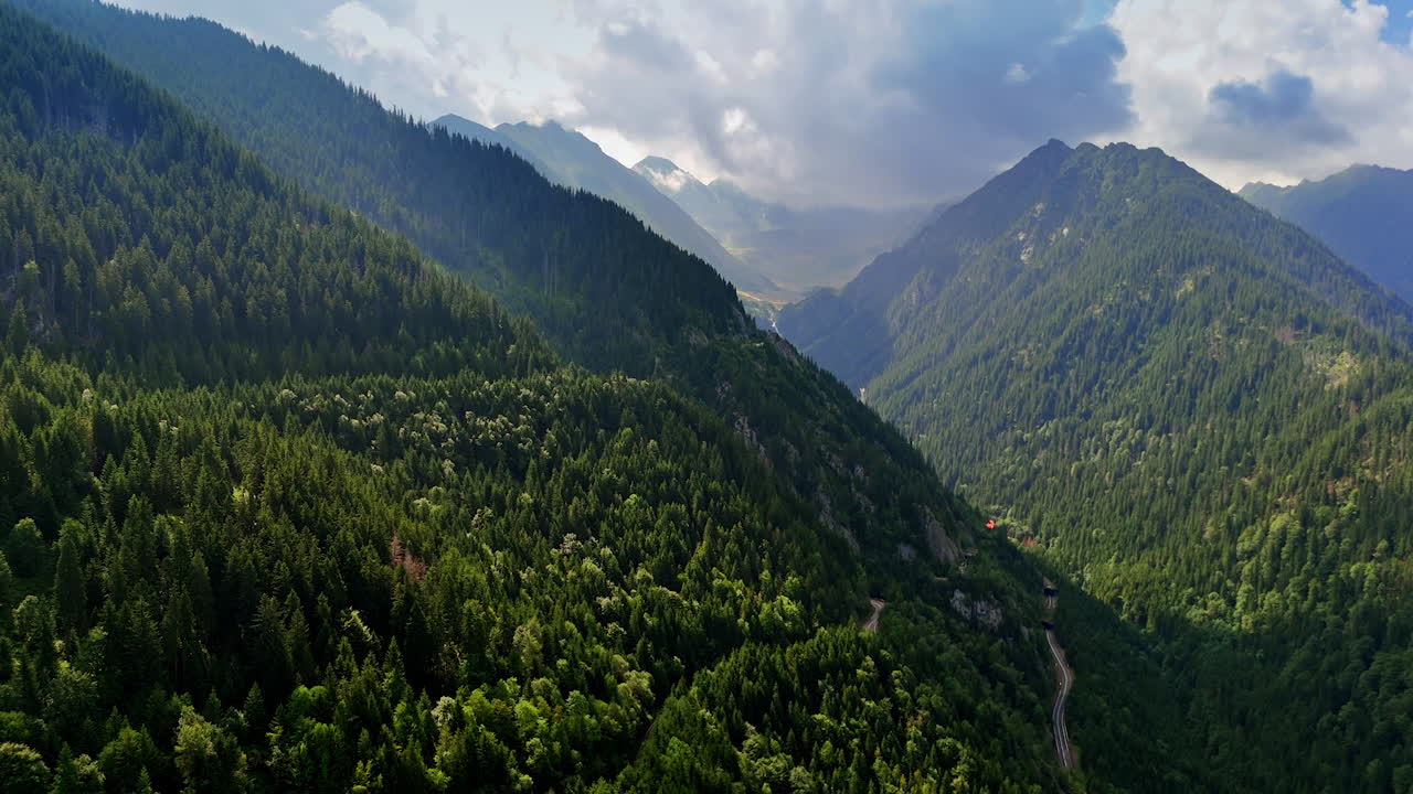 Mountain slopes and forest in Fagaras Mountains, Romania. Drone view of green forested slopes of the Fagaras Mountains with layered ridges fading into the misty horizon in Romania