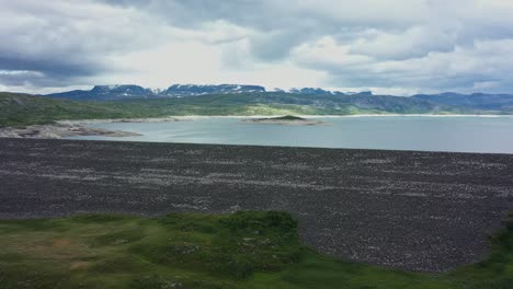 Aerial-overview-showing-massive-Sysen-dam-Hardangervidda-Norway-and-water-level-inside---Low-water-level-during-ricing-electricity-prices-in-Europe